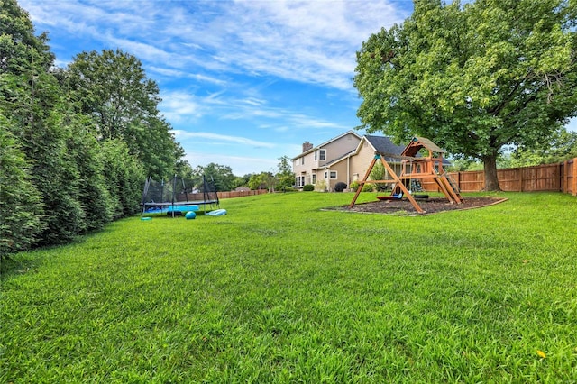 view of yard with a trampoline, fence, and a playground