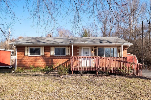 view of front facade featuring brick siding, a deck, and a front lawn