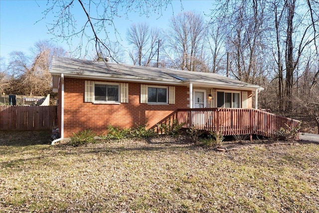 view of front of property with a deck, a front lawn, fence, and brick siding