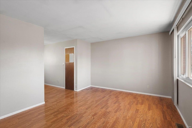 spare room featuring visible vents, baseboards, and wood finished floors