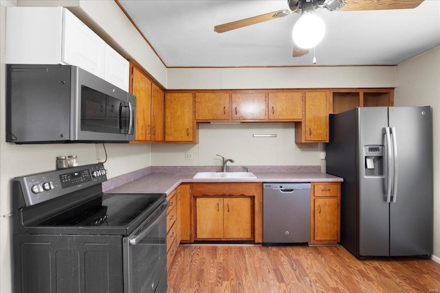 kitchen with light countertops, light wood-style flooring, brown cabinets, stainless steel appliances, and a sink