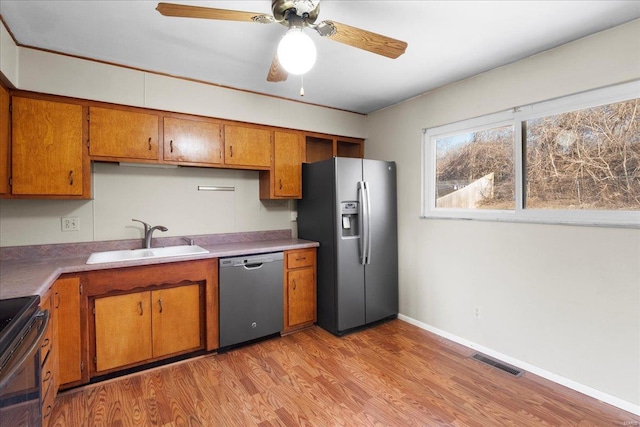 kitchen featuring light wood-type flooring, visible vents, a sink, stainless steel appliances, and brown cabinetry