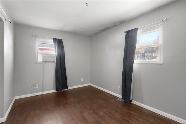 unfurnished room with visible vents, cooling unit, baseboards, and wood finished floors