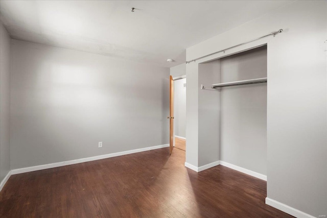 unfurnished bedroom featuring a closet, baseboards, and wood finished floors