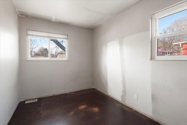 unfurnished room featuring visible vents and dark wood finished floors