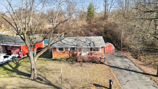 view of front facade with a front yard, brick siding, and driveway