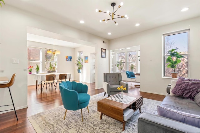 living area with baseboards, recessed lighting, wood finished floors, and a notable chandelier