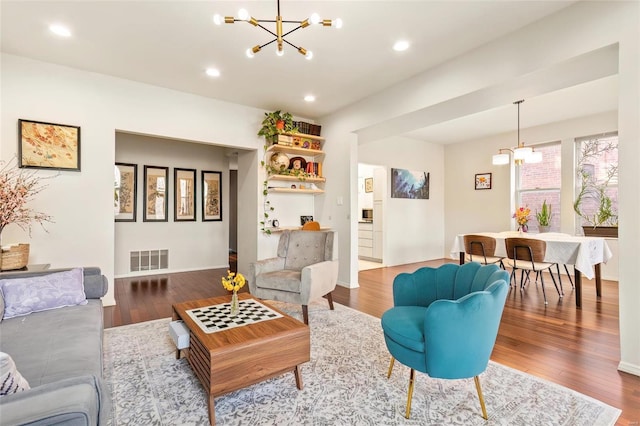 living area with recessed lighting, wood finished floors, visible vents, and an inviting chandelier