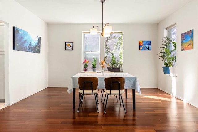 dining area with a chandelier, dark wood-style flooring, and baseboards