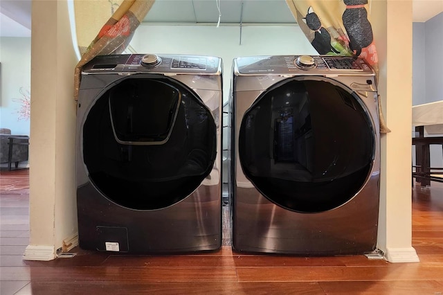 clothes washing area with laundry area, wood finished floors, and independent washer and dryer