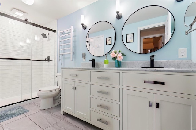 full bath featuring a sink, double vanity, a shower stall, and toilet