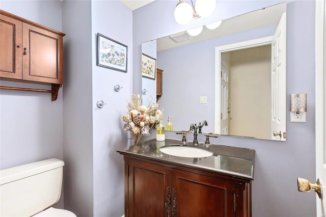 bathroom with toilet, visible vents, and vanity