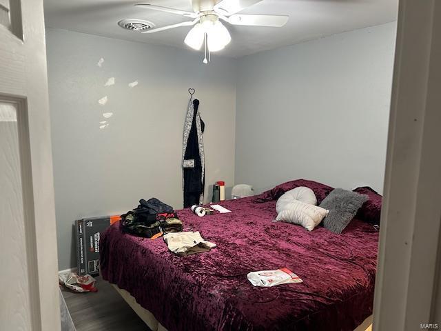 bedroom featuring a ceiling fan, visible vents, and wood finished floors