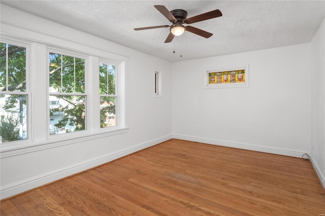 empty room featuring ceiling fan, a textured ceiling, baseboards, and wood finished floors