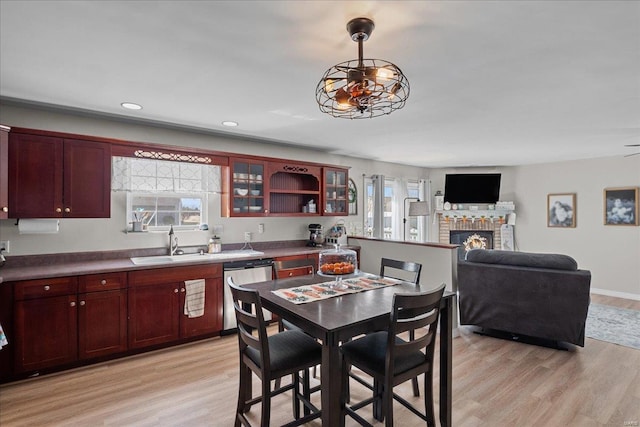 kitchen with reddish brown cabinets, light wood-style floors, a sink, and dishwasher