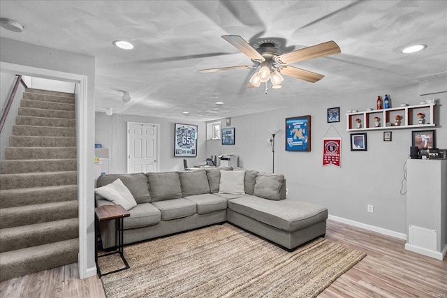 living area with stairway, baseboards, light wood-style flooring, and a textured ceiling