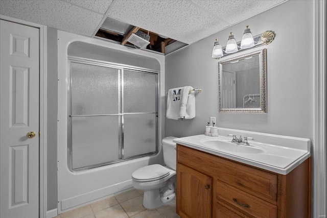 full bathroom featuring a drop ceiling, toilet, tile patterned floors, combined bath / shower with glass door, and vanity