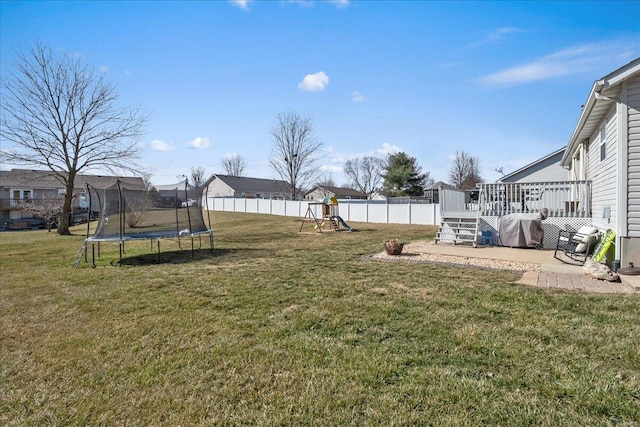 view of yard with a trampoline, fence, a deck, a patio area, and a playground