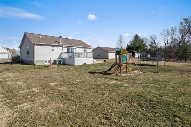 rear view of house with a trampoline, a playground, and a yard