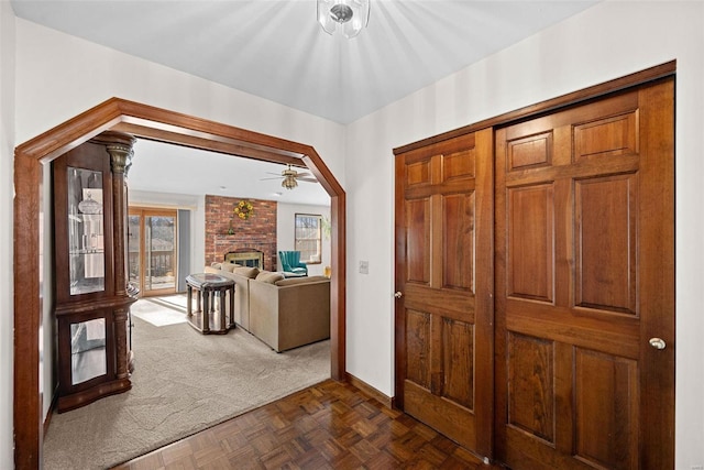 foyer featuring dark carpet, baseboards, arched walkways, and a fireplace