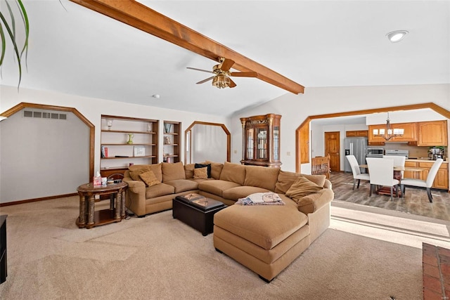 living area featuring carpet, visible vents, baseboards, vaulted ceiling with beams, and ceiling fan with notable chandelier