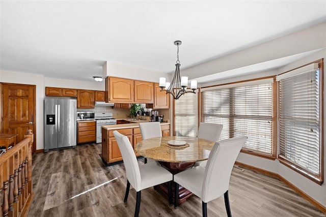 dining space featuring dark wood finished floors, baseboards, and an inviting chandelier