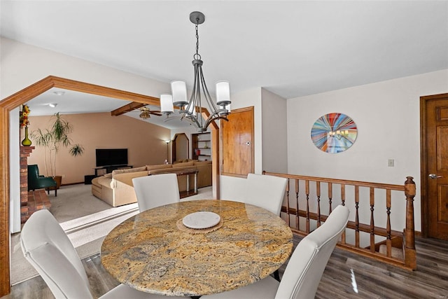 dining space featuring wood finished floors, vaulted ceiling with beams, ceiling fan with notable chandelier, and baseboards