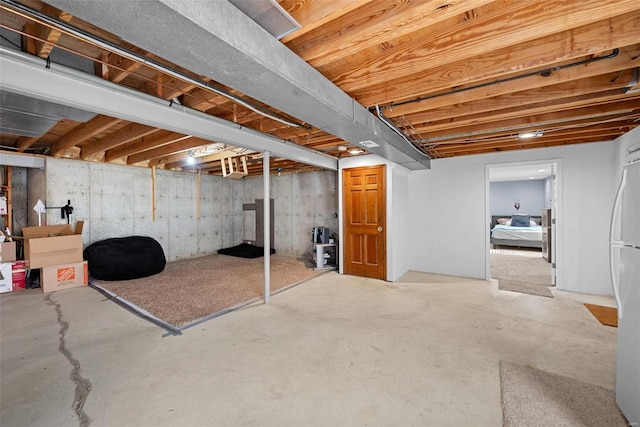 unfinished basement with freestanding refrigerator