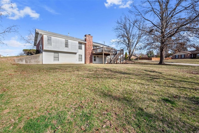 rear view of house with a lawn, a chimney, a deck, and stairs