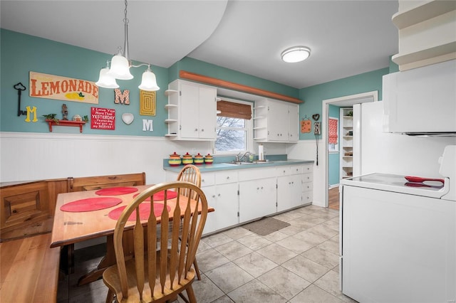 kitchen featuring open shelves, wainscoting, washer / dryer, white cabinets, and a sink