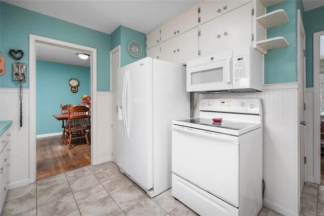 kitchen featuring light countertops, wainscoting, white appliances, white cabinetry, and open shelves