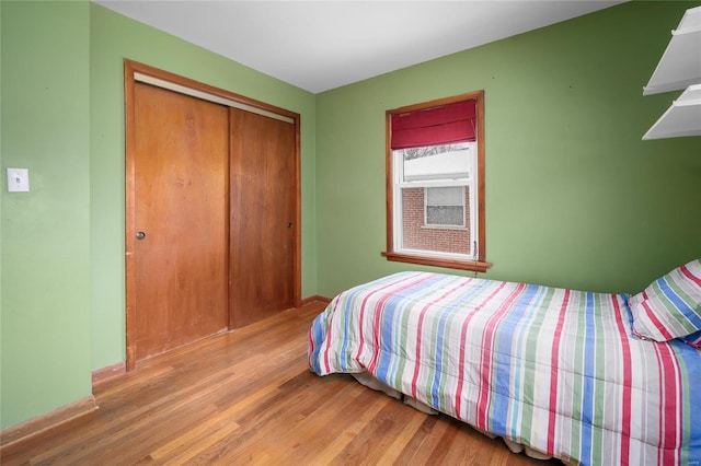 bedroom featuring wood finished floors, a closet, and baseboards