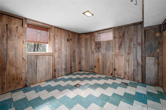 spare room featuring tile patterned floors and wooden walls