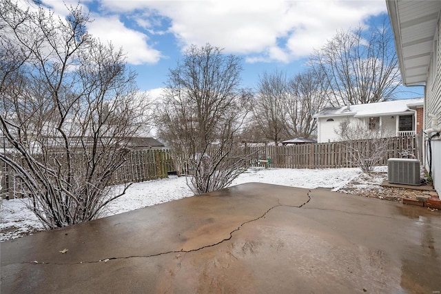 yard layered in snow featuring a patio area, central air condition unit, and fence