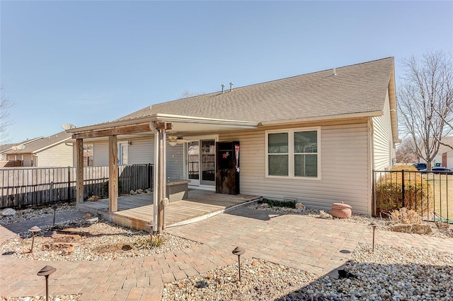 back of property featuring a shingled roof, fence, and a patio