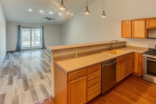 kitchen with light countertops, appliances with stainless steel finishes, a sink, wood finished floors, and a peninsula