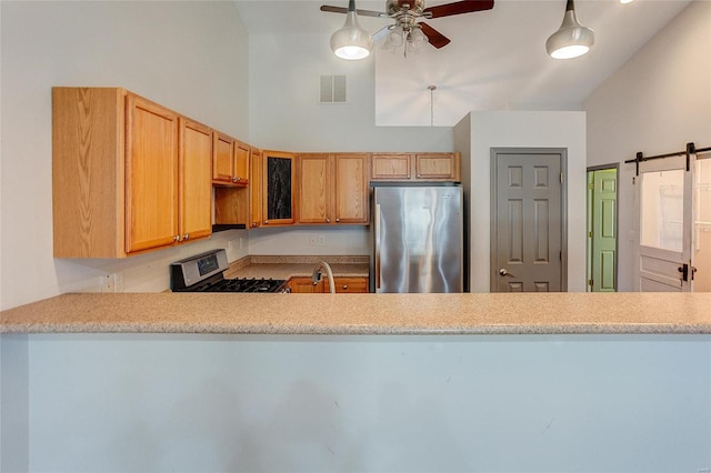 kitchen with a barn door, visible vents, ceiling fan, appliances with stainless steel finishes, and light countertops