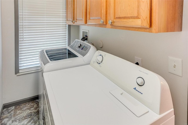 clothes washing area with cabinet space, baseboards, and washer and dryer