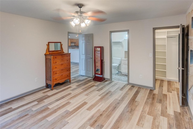 bedroom featuring a closet, a walk in closet, light wood-style flooring, and baseboards