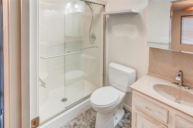 bathroom with a shower stall, toilet, and vanity