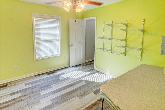 spare room with ceiling fan, wood finished floors, visible vents, and baseboards