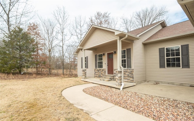 view of front facade featuring stone siding and roof with shingles