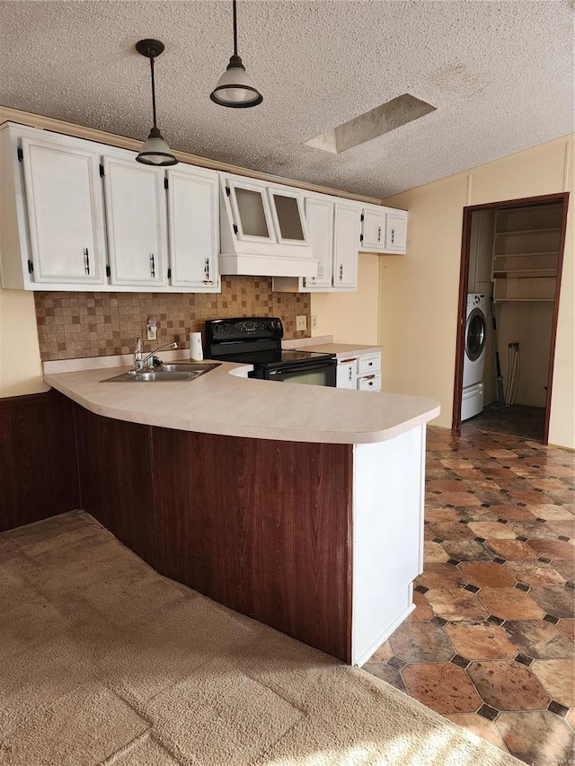 kitchen featuring white cabinets, a sink, washer / dryer, black range with electric cooktop, and a peninsula