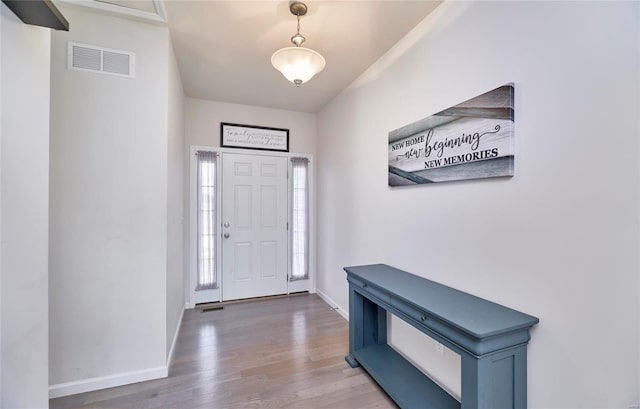 foyer entrance with visible vents, baseboards, and wood finished floors