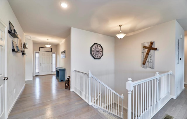 hall featuring baseboards, an upstairs landing, and wood finished floors