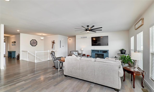 living room featuring light wood-type flooring, visible vents, and ceiling fan