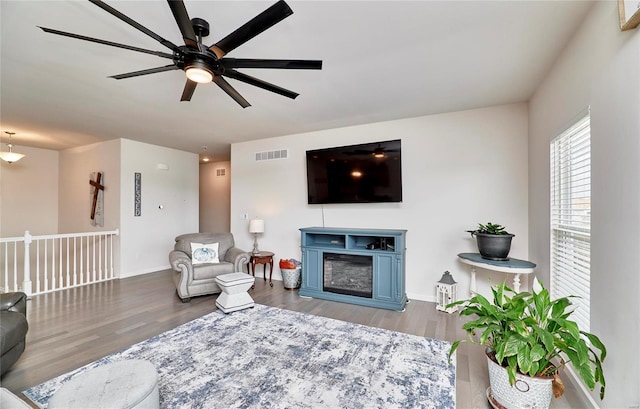 living area featuring visible vents, a fireplace, baseboards, and wood finished floors