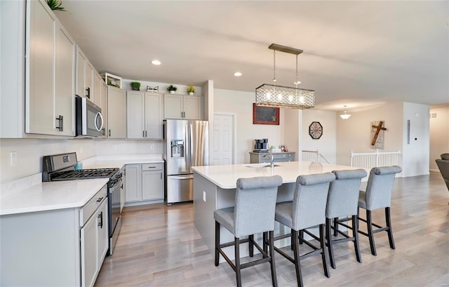 kitchen featuring a kitchen bar, light wood-style floors, appliances with stainless steel finishes, and a sink