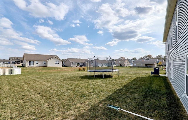 view of yard with a residential view, a trampoline, and fence