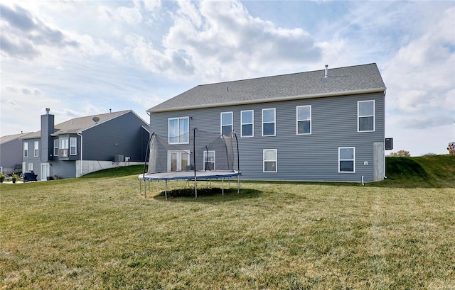 rear view of house featuring a lawn and a trampoline